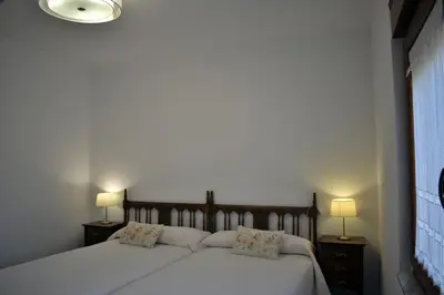 a bedroom with two beds with white sheets and two lamps at Apartamentos Picea Azul in Vega de Espinareda
