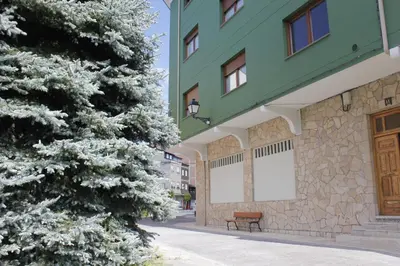 a bench in front of a building with a snow covered tree at Apartamentos Picea Azul in Vega de Espinareda