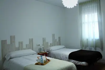 a bedroom with two beds and a chandelier at MON ComeySueña Guesthouse in Monforte de Lemos