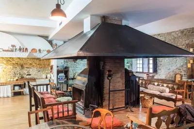 a large fireplace in a room with tables and chairs at La Casa Del Reloj in Molinaseca