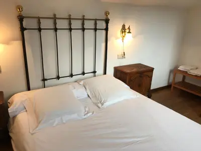 a bedroom with a large bed with white sheets at La Casa Del Reloj in Molinaseca