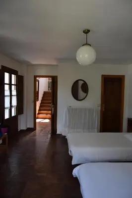 a bedroom with two beds and a hallway with stairs at La Casa Del Reloj in Molinaseca