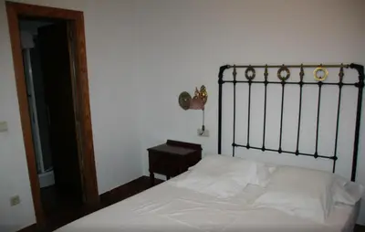 a bedroom with a white bed with a metal headboard at La Casa Del Reloj in Molinaseca