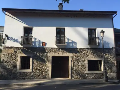 a white building with windows and balconies and a street light at La Casa Del Reloj in Molinaseca