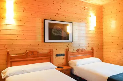 two beds in a room with wooden walls at Alda Palas de Rei in Palas de Rei