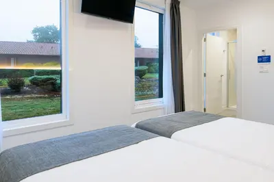 two beds in a bedroom with two windows at Alda Palas de Rei in Palas de Rei