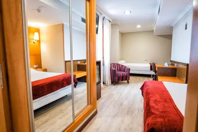 a hotel room with two beds and a mirror at Hotel Alda Bonaval in Santiago de Compostela