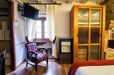 a bedroom with a bed and a chair and a television at Hotel Alda Bonaval in Santiago de Compostela