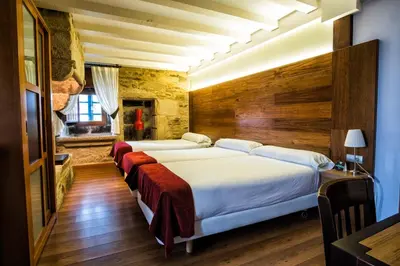 two beds in a room with wooden walls at Hotel Alda Bonaval in Santiago de Compostela