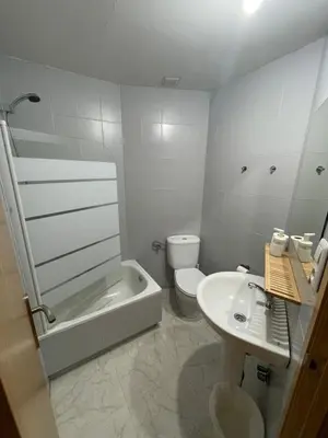 a white bathroom with a toilet and a sink at Pension Valcarce in Ponferrada
