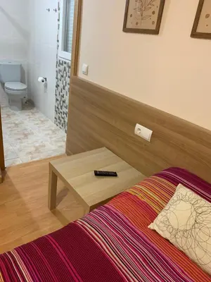 a bedroom with a bed and a table and a toilet at Pension Valcarce in Ponferrada