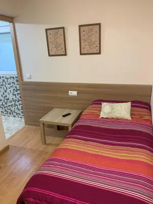 a bedroom with a bed and a wooden table at Pension Valcarce in Ponferrada