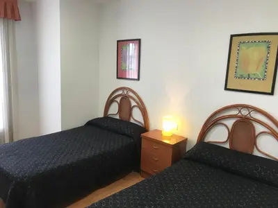 a bedroom with two beds and a lamp on a dresser at Hostal Las Eras in Cubillos del Sil