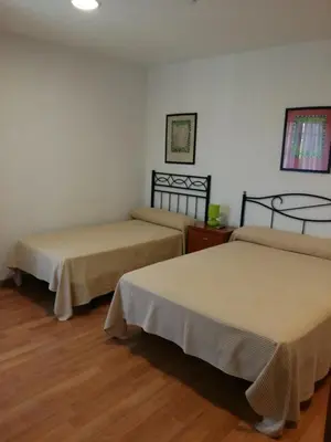 two beds in a room with wooden floors at Hostal Las Eras in Cubillos del Sil