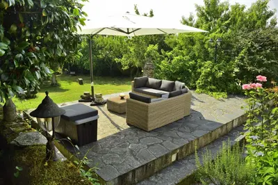 a patio with a couch and an umbrella at Pazo Torre Do Barrio in Loseiro