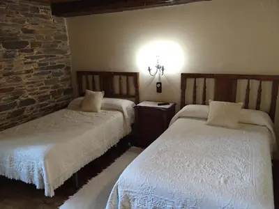 a bedroom with two beds and a brick wall at Pazo Torre Do Barrio in Loseiro