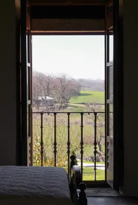 a bedroom with a large window looking out at a field at Pazo Torre Do Barrio in Loseiro