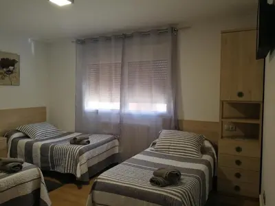 a room with two beds and a dresser and a window at Hospedaje Jose Rey in Santiago de Compostela