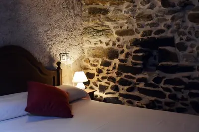 a dining room with a table and chairs and a stone wall at Casa Rural Xiromo in San Ciprián