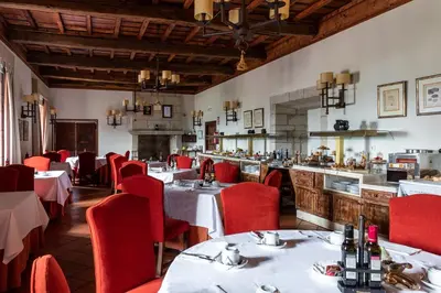 a restaurant with tables and red chairs and a counter at Parador de Monforte de Lemos in Monforte de Lemos