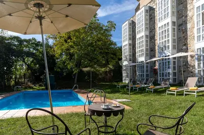 a table and chairs with an umbrella next to a pool at Parador de Monforte de Lemos in Monforte de Lemos