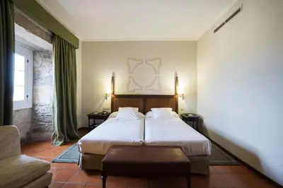 a hotel room with a bed and a chair at Parador de Monforte de Lemos in Monforte de Lemos