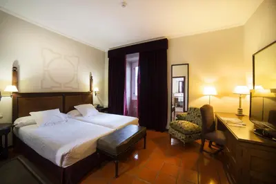 a hotel room with a large bed and a desk and chair at Parador de Monforte de Lemos in Monforte de Lemos