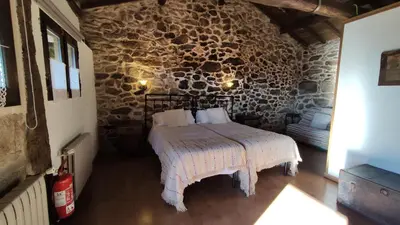 a bedroom with a bed and a stone wall at Aldea Rural Santo André in Congostro