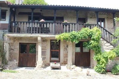 a stone house with a balcony and a deck at Aldea Rural Santo André in Congostro