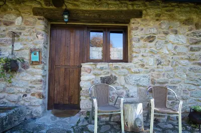 a stone building with two chairs and a wooden door at Aldea Rural Santo André in Congostro