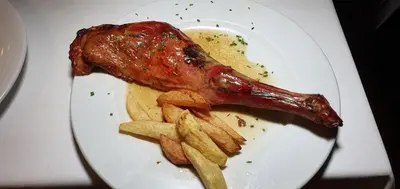 a plate of food with a piece of meat and french fries at Hotel Molina Real in Molinaseca