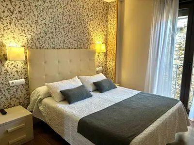 a bedroom with a large bed with two blue pillows at Hotel Molina Real in Molinaseca