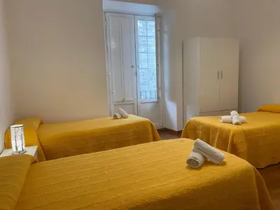 three beds in a room with yellow sheets at Pensión Hedrass in Santiago de Compostela