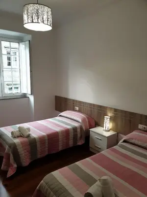 a bedroom with two beds and a window at Pensión Hedrass in Santiago de Compostela