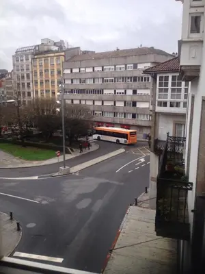 a bus driving down a city street with buildings at Pensión Hedrass in Santiago de Compostela