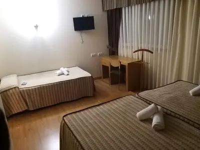 a hotel room with two beds and a desk at Hotel Condes De Lemos España in Monforte de Lemos