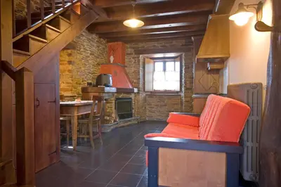 a living room with a red chair and a kitchen at Balcón de Oscos in Santa Eulalia de Oscos