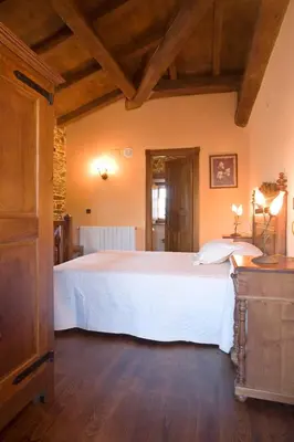 a bedroom with a large white bed and wooden floors at Balcón de Oscos in Santa Eulalia de Oscos