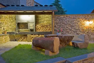a stone building with a stone bench in a yard at Balcón de Oscos in Santa Eulalia de Oscos