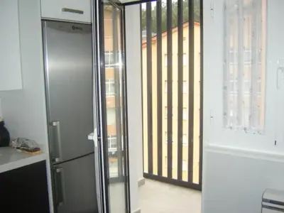 a kitchen with a stainless steel refrigerator and a balcony at Apartamento Viveiro, Terraza Grande, 2 dormitorios 2 baños, piscinas, parking, tenis, club social in Jove