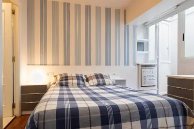 a bedroom with a bed with a blue and white plaid blanket at Pension Residencia F&F in Santiago de Compostela