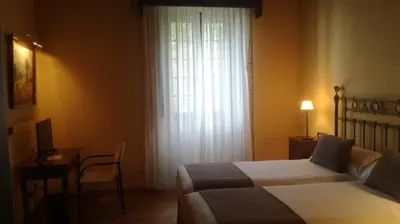 a bedroom with two beds and a desk and a window at Pazo da Merced in Neda