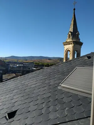 a church steeple with a clock tower on top of a roof at Hostal Siglo XIX in Cacabelos