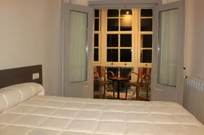 a bedroom with a white bed and a table and chairs at Hostal Siglo XIX in Cacabelos