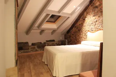 a bedroom with a bed and a stone wall at Hostal Siglo XIX in Cacabelos
