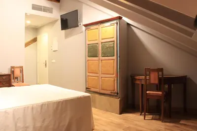 a bedroom with a bed and a table and a window at Hostal Siglo XIX in Cacabelos