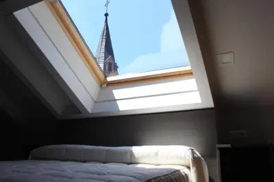 a bed in a room with a window with a tower at Hostal Siglo XIX in Cacabelos