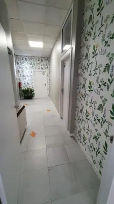a hallway with a white tile floor and green wallpaper at Albergue Turistico la Credencial in Santiago de Compostela