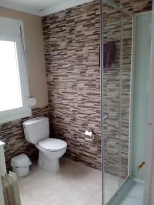 a bathroom with a toilet and a glass shower at Albergue Aqua Portomarin in Portomarin