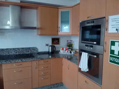 a kitchen with wooden cabinets and a stove top oven at Albergue Aqua Portomarin in Portomarin